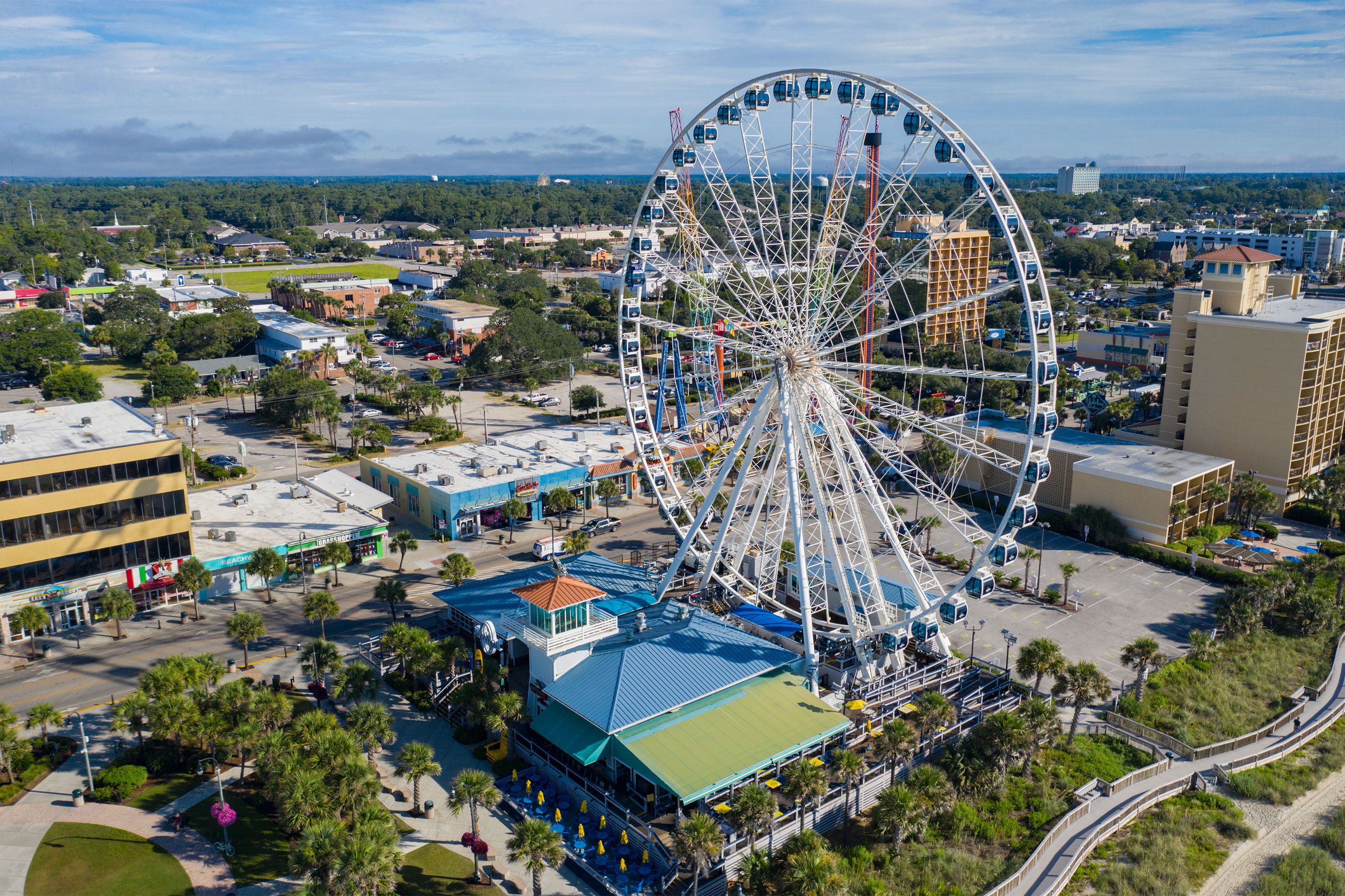 The SkyWheel Ferris wheel towering by the Myrtle Beach shoreline with buildings in the background.