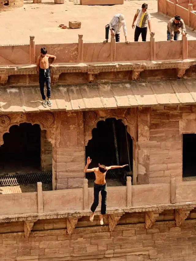 A young boy jumps from a balcony of the Toorji Ka Jhalra stepwell in Jodphur, India, to the water below