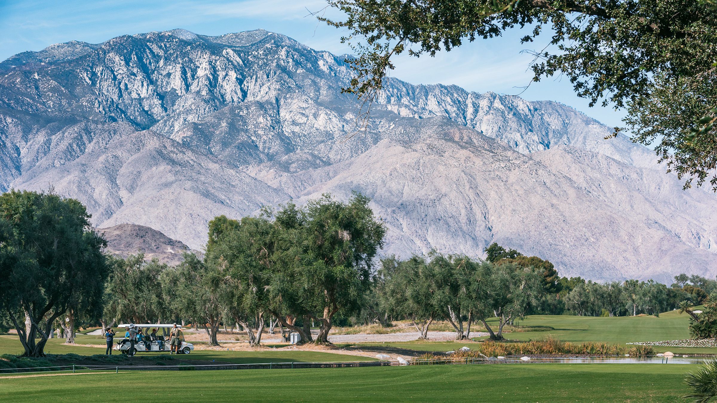 Views of sprawling golf course surrounded by mountains, Palm Springs, California during a sunny afternoon