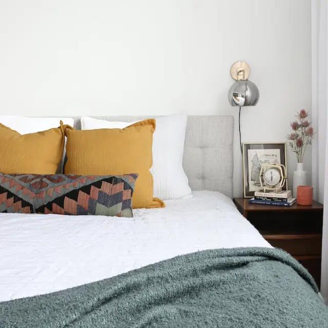 A cozy bedroom with ochre and patterned cushions