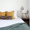 A cozy bedroom with ochre and patterned cushions