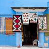 Brightly colored textiles hang outside a sky-blue building in Oaxaca, Mexico