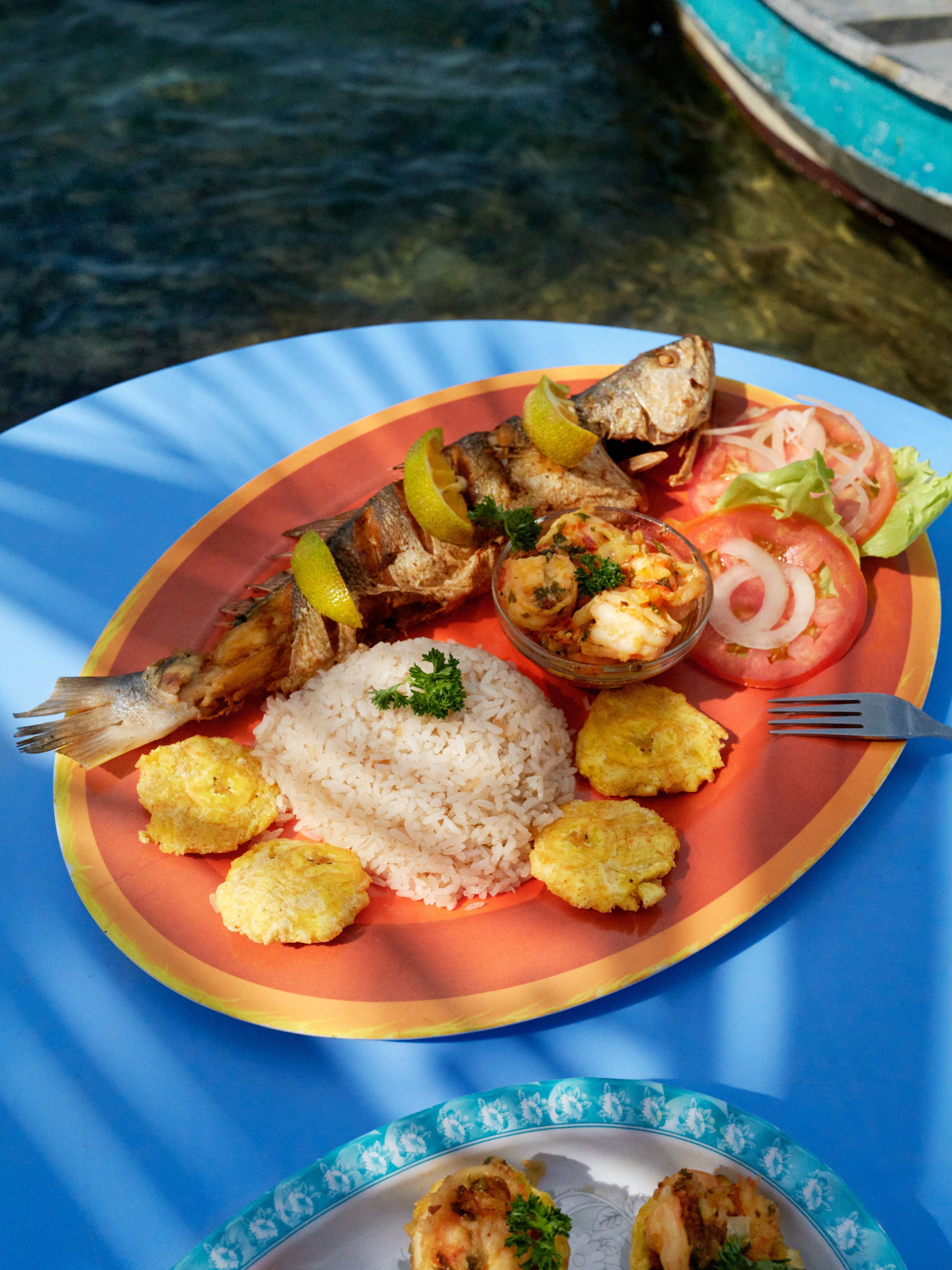 A dish of whole fried corvina fish, garnished with lemon wedges, served with rich and fried plantains, at Restaurante Adriana, Colón, Panama