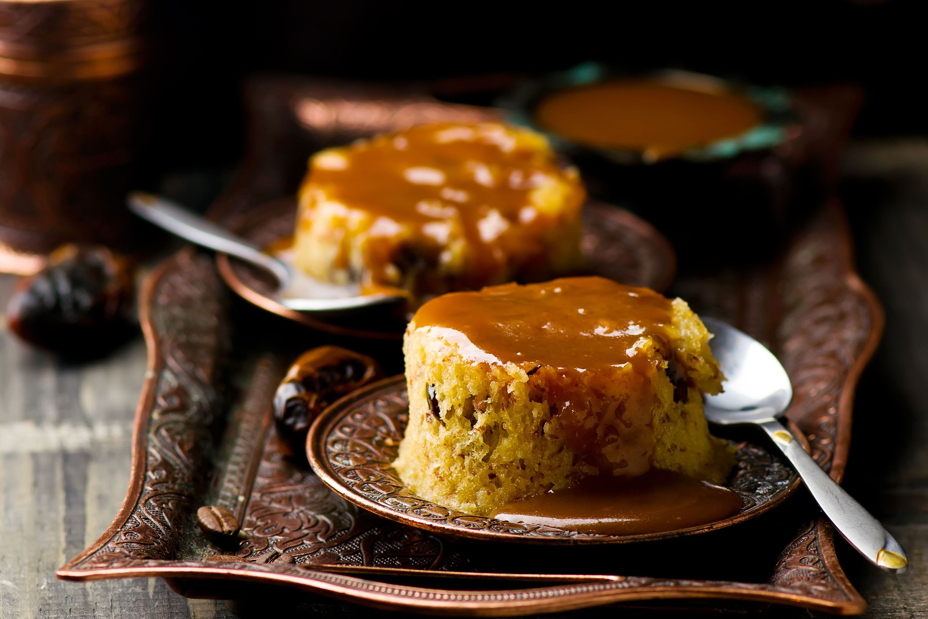Date pudding with caramel on a plate with a spoon. 