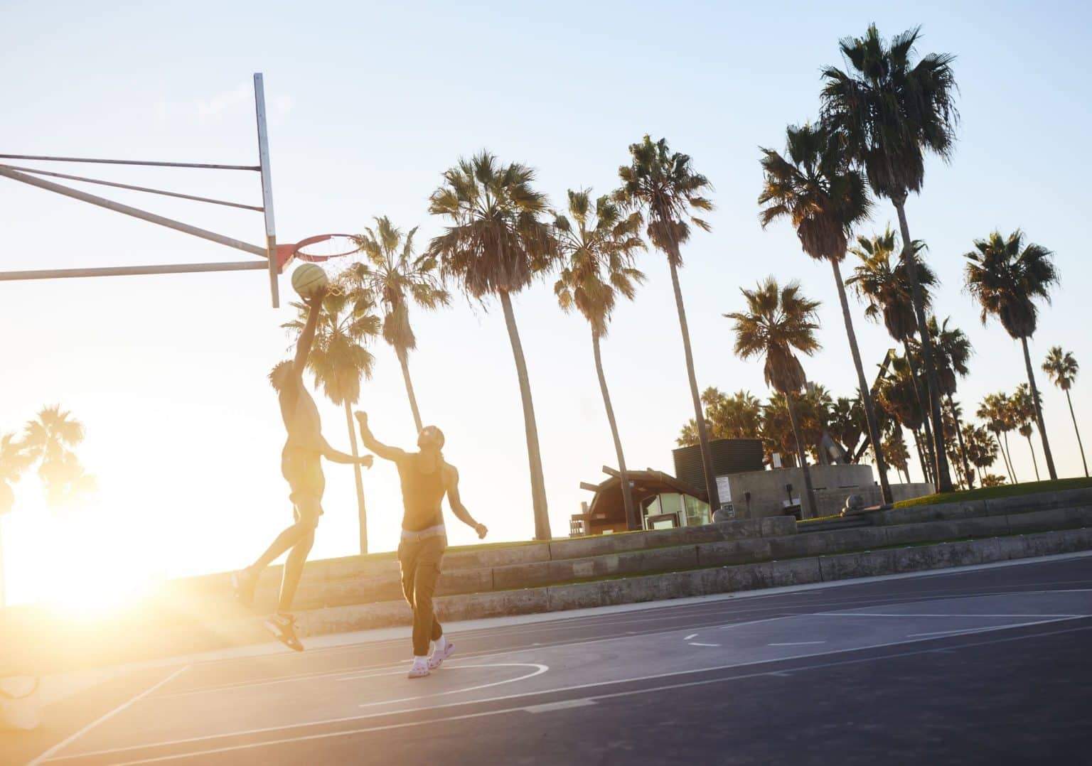 Basketball players shoot hoops at a court on Venice Beach, California