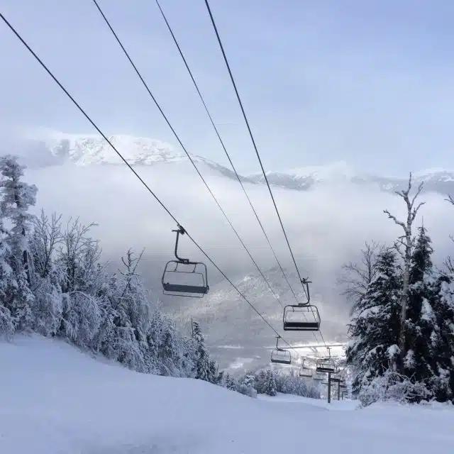 A ski chairlift on a snowy mountain covered with trees