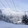 A ski chairlift on a snowy mountain covered with trees