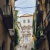 People walk up a set of stone stairs between residential buildings with balconies in Girona, Spain
