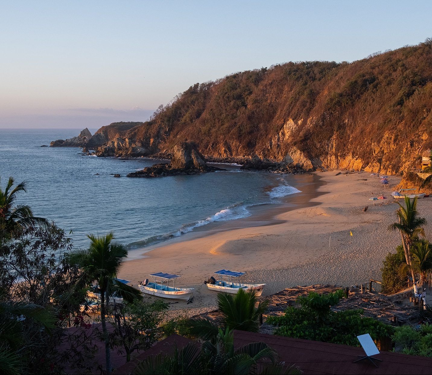 The beach at Mazunte, Mexico, with boats pulled up onto the shore, and waves lapping