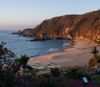 The beach at Mazunte, Mexico, with boats pulled up onto the shore, and waves lapping
