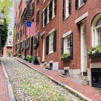 Red-brick buildings with shuttered windows line a cobbled street in Boston, Massachussets