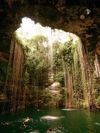 Sunlight pours through the lush, vine-covered opening onto the waters of Ik Kil cenote in Cancun, Mexico