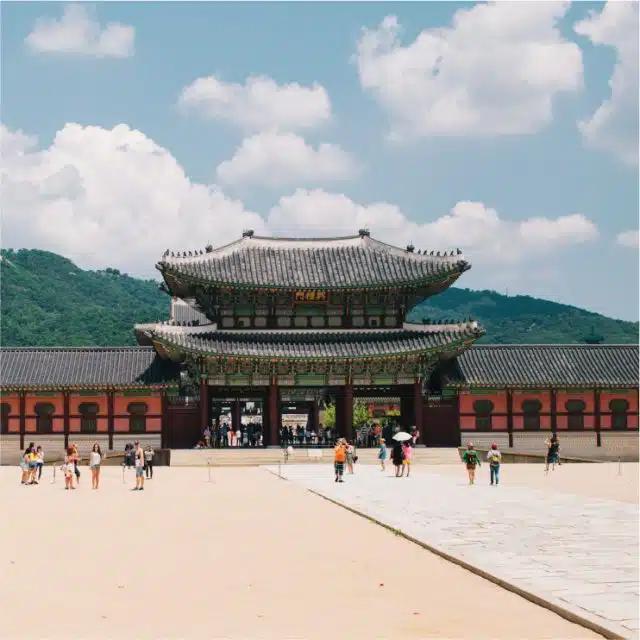 The must-see Gyeongbokgung Palace, Seoul, with hills in the background and a few lone visitors in the foreground