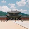 The must-see Gyeongbokgung Palace, Seoul, with hills in the background and a few lone visitors in the foreground