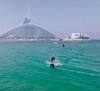 A contestant on The Amazing Race glides across Dubai Harbour on an eFoil electric surfboard in Dubai, UAE