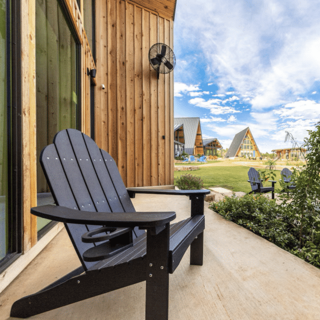 An Adirondack chair on the veranda of a wood A-frame cabin Vrbo in Texas