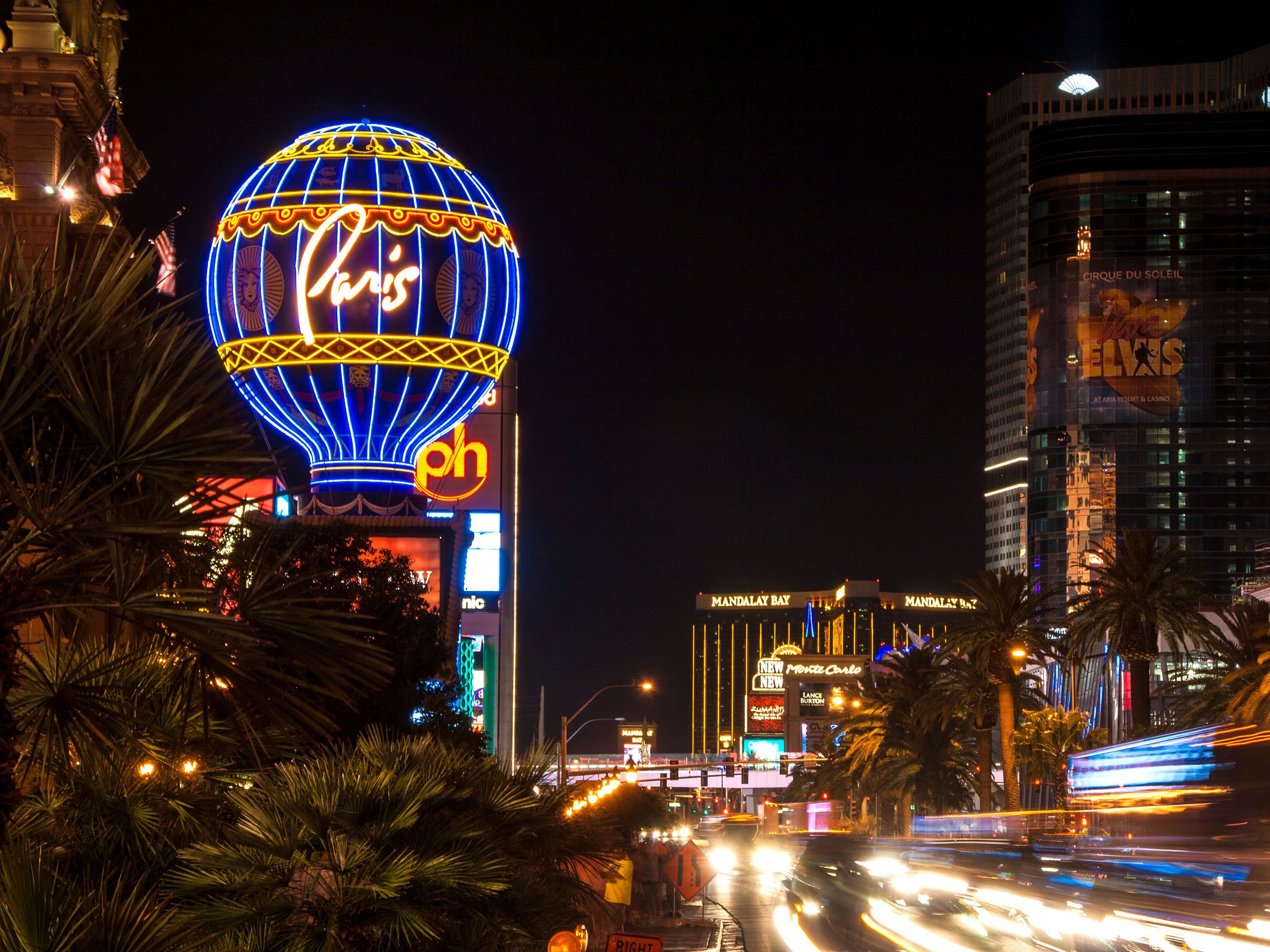 Paris Las Vegas sign at night with cars speeding by.