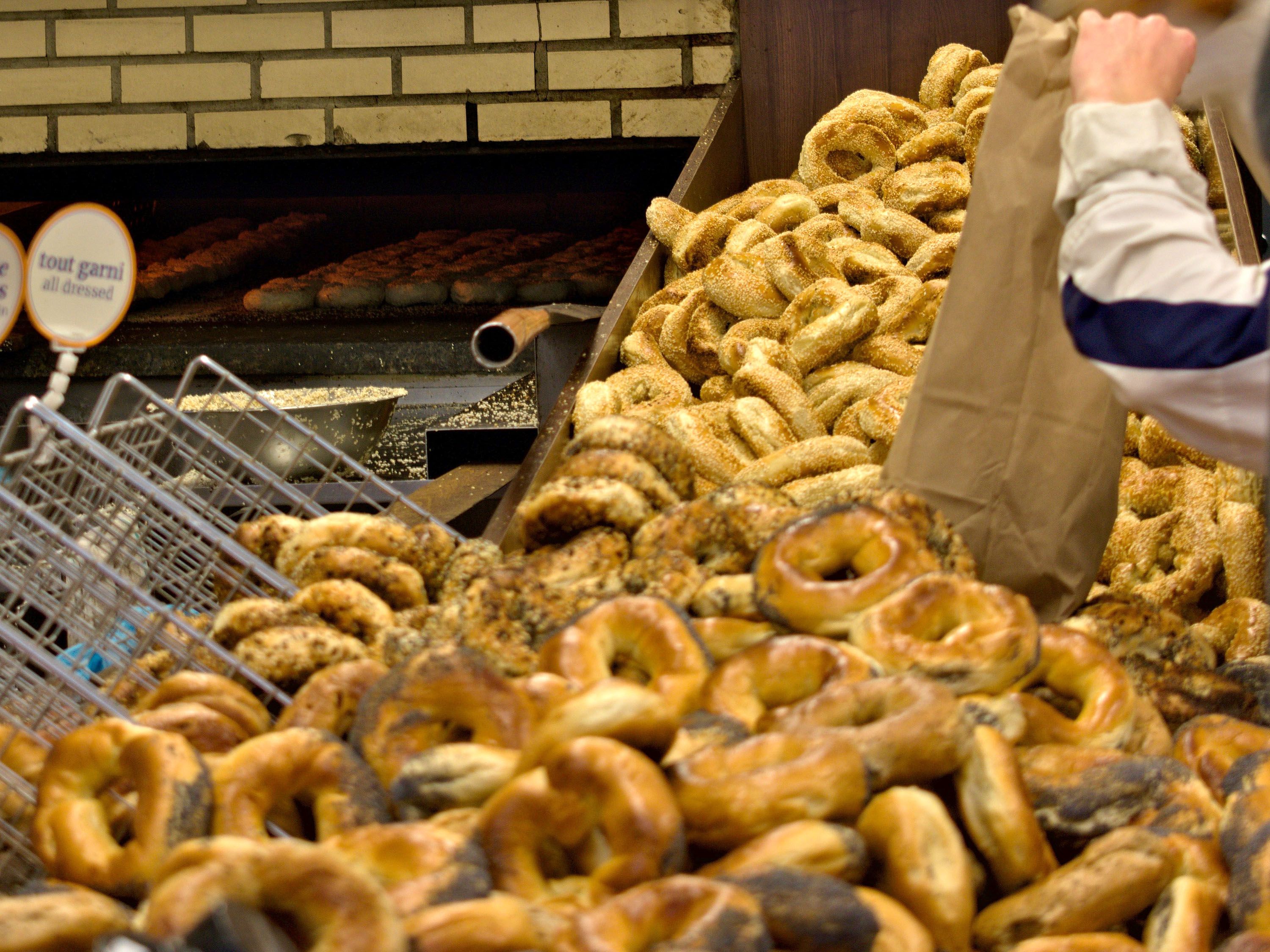 Piles of fresh bagels come out of a wood-fire oven.
