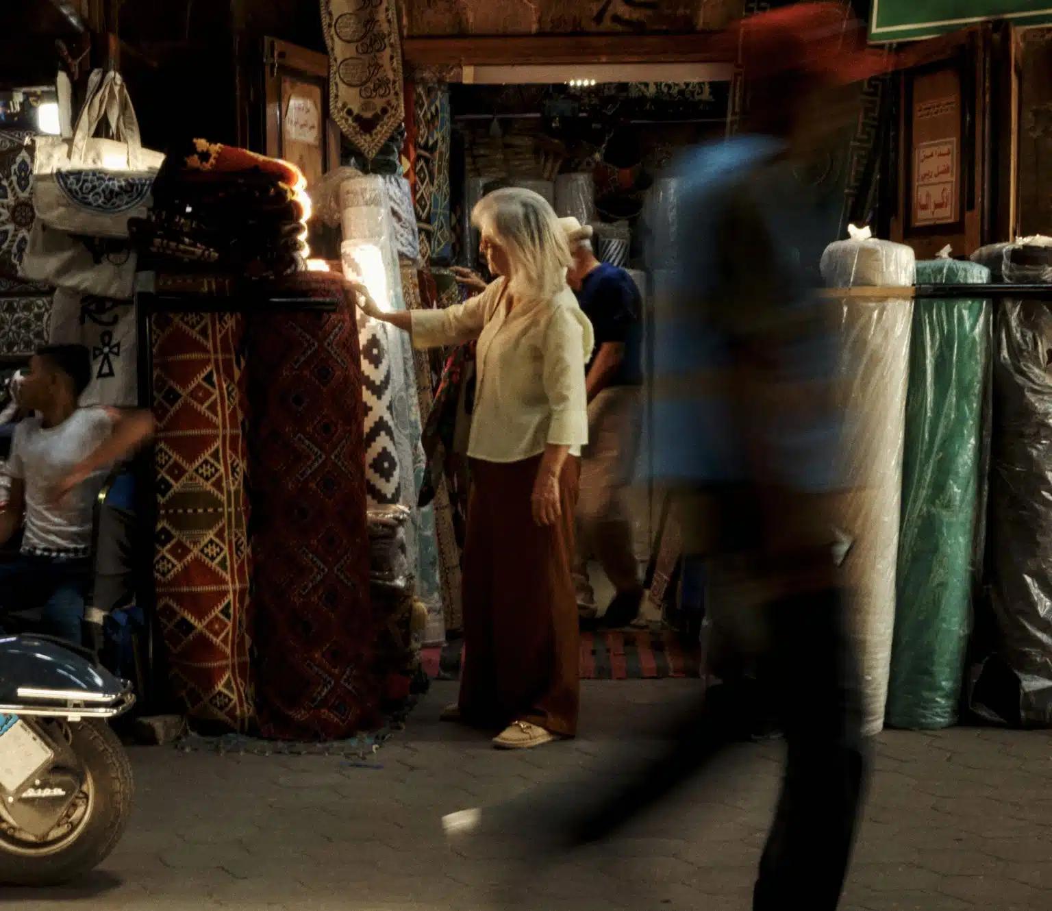 A woman reaches out to touch a rolled-up rug outside a carpet store in Egypt