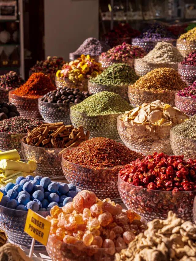 Glass bowls piled high with colorful spices and dried fruit on a Dubai market stall