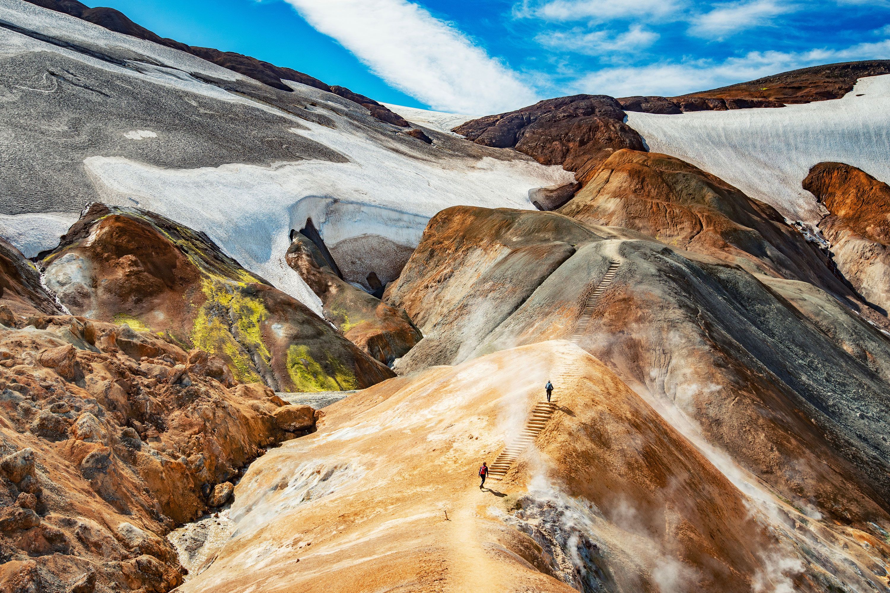 Two people hiking on the colorful Kerlingarfjöll mountain range in Iceland.