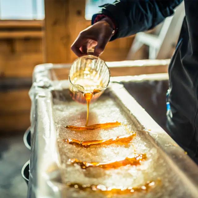 Maple syrup is poured on a table covered in snow to form candy at a local sugar shack