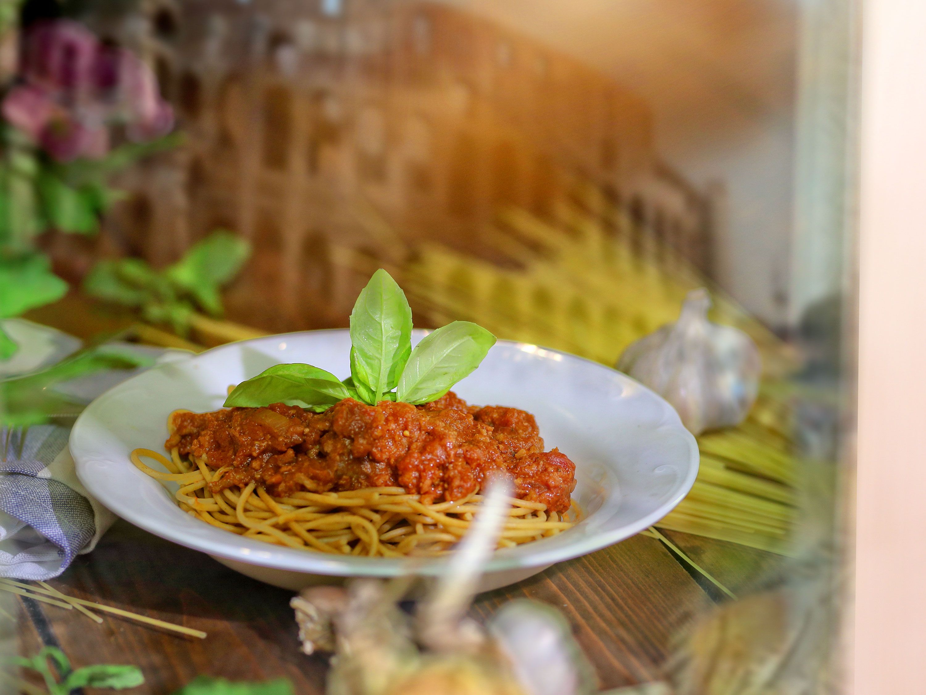 Plate of spaghetti with rich tomato meat sauce and fresh basil garnish.