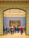 Rembrandt’s painting The Night Watch at the Rijksmuseum in Amsterdam, seen through an archway with a crowd assem