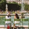 Two young women sit on the chairs by the fountain in Jardin des Tuileries in Paris, France