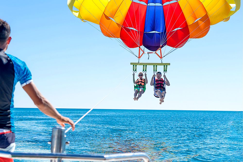 Two people setting out parasailing from a boat.