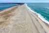 An aerial photo of a sandy beach with water on either side.