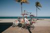 People cycle along a beachfront path in Florida with palm trees, sand and sea in the background