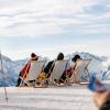 People recline on deckchairs atop a mountain on a sunny day in the French Alps