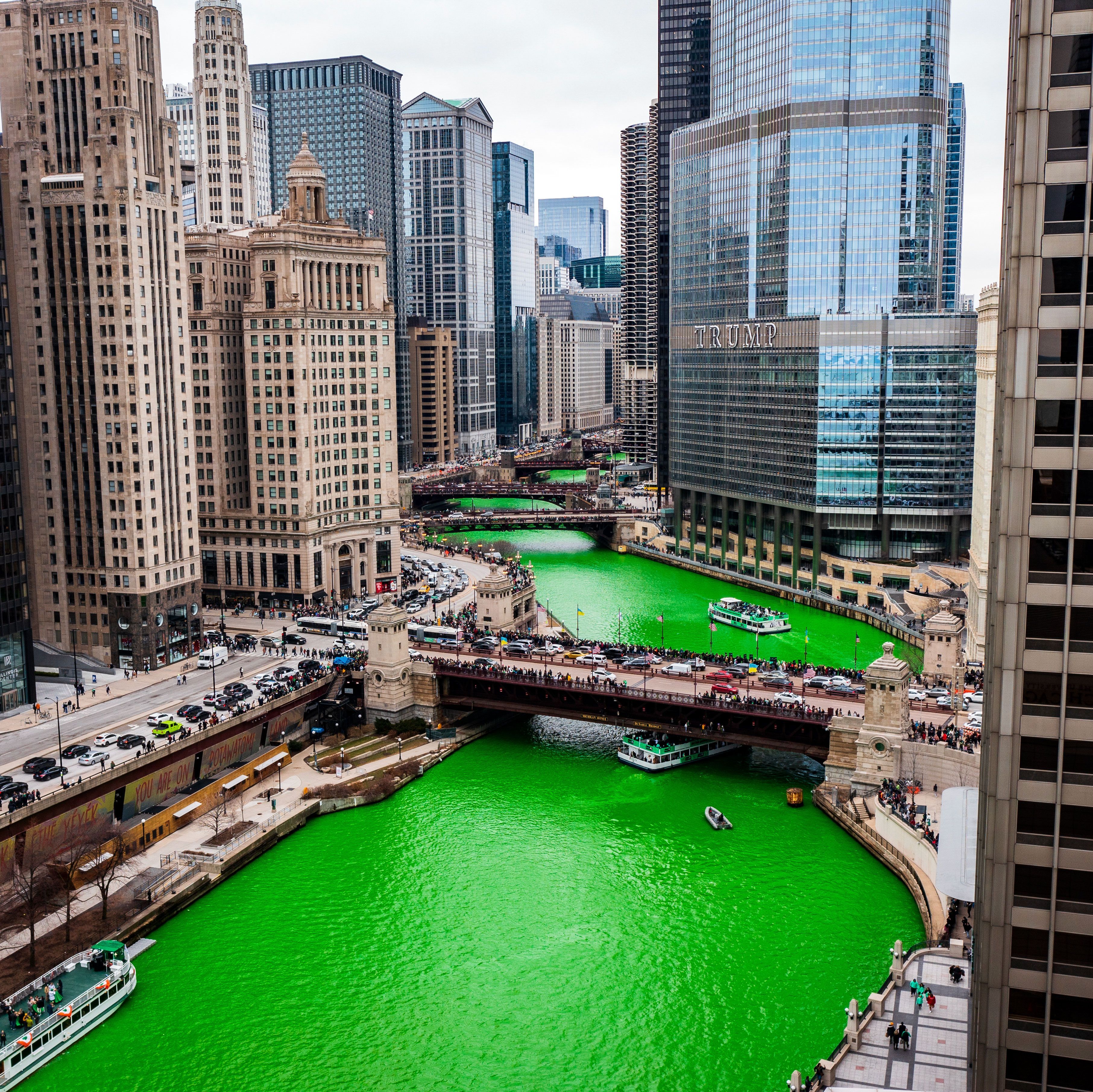 A river dyed bright green downtown a city.