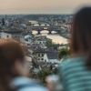 Two people seen blurred from behind look out to Ponte Vecchio from Piazzale Michelangelo in Florence, Italy