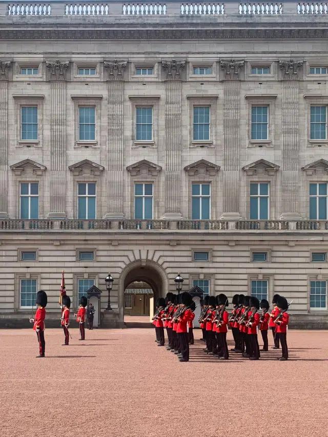 Soldiers wearing traditional red coats and bearskin hats in the King's Guards perform the Changing of the Guard at Buckingham Palace