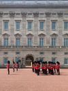 Soldiers wearing traditional red coats and bearskin hats in the King's Guards perform the Changing of the Guard at Buckingham Palace