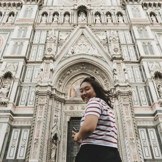 A woman looks back and smiles outside Santa Maria del Fiore cathedral in Florence, Italy