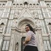A woman looks back and smiles outside Santa Maria del Fiore cathedral in Florence, Italy