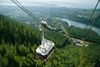 A cable car zips up the steep incline of Grouse Mountain with a blanket of evergreens covering the slope below