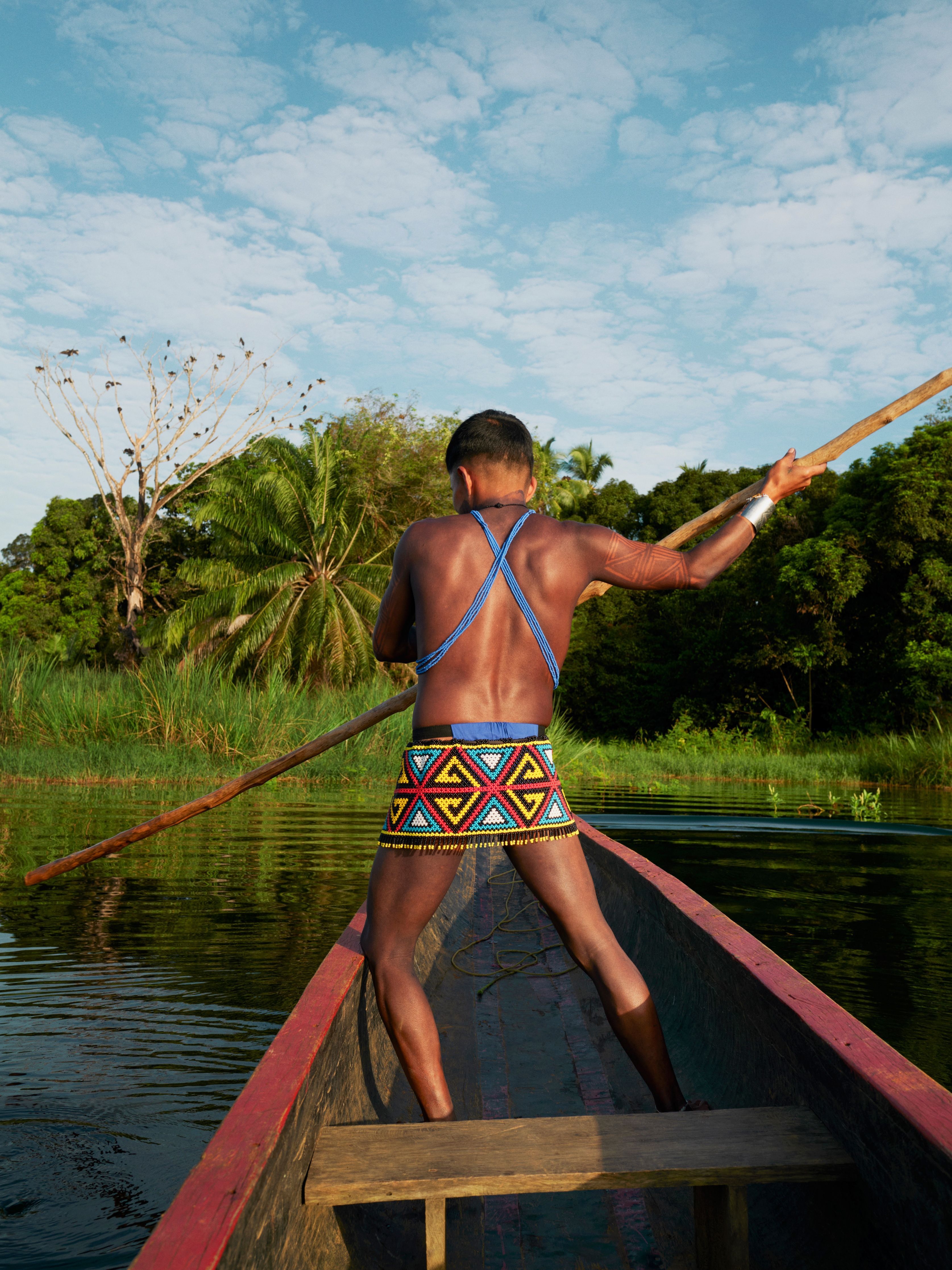 A member of the Emberá tribal community steers a wooden canoe with a long pole along the Chagres River in Panama 