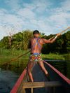 A member of the Emberá tribal community steers a wooden canoe with a long pole along the Chagres River in Panama