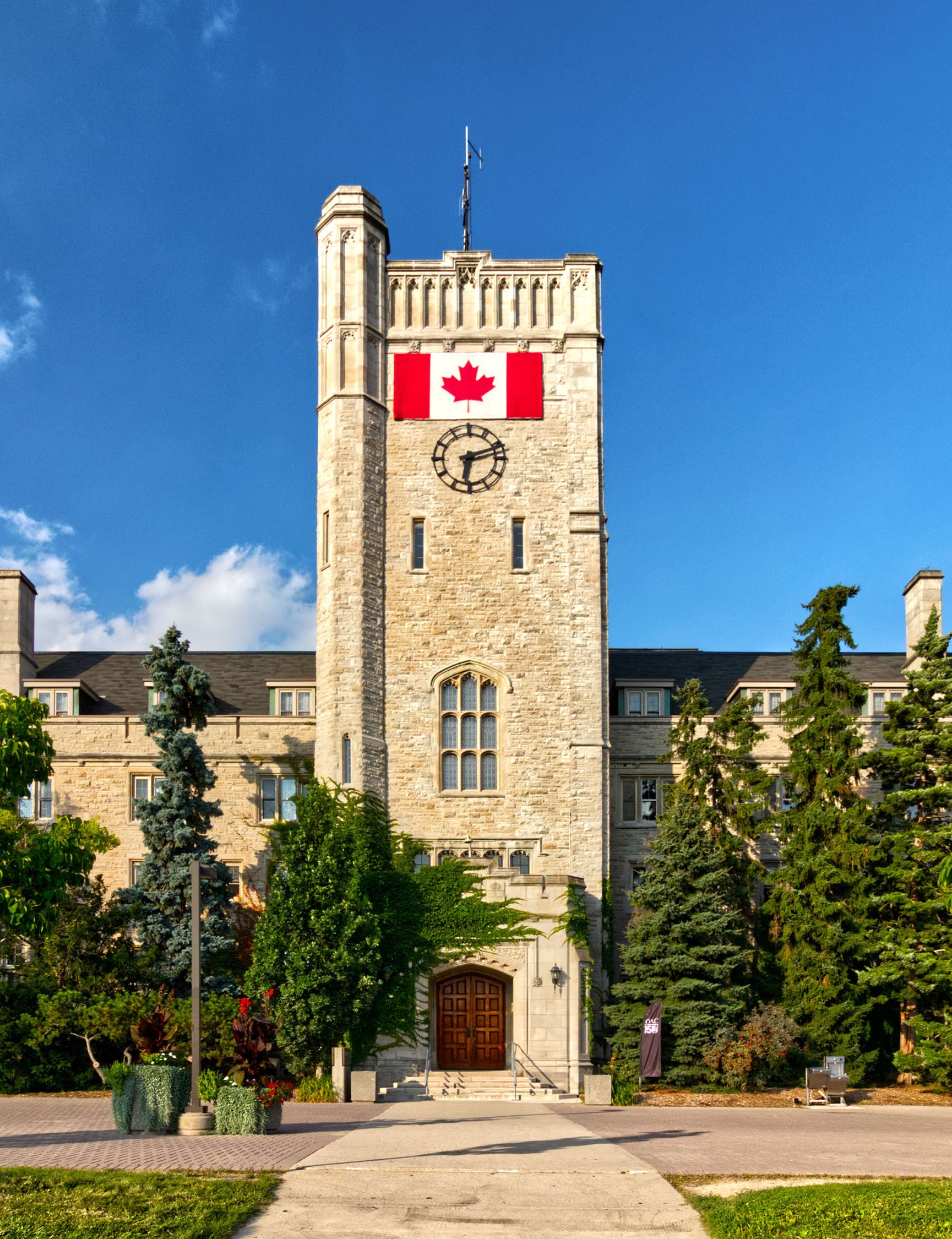 Sidewalk leading to campus building adorned with Canadian flag.