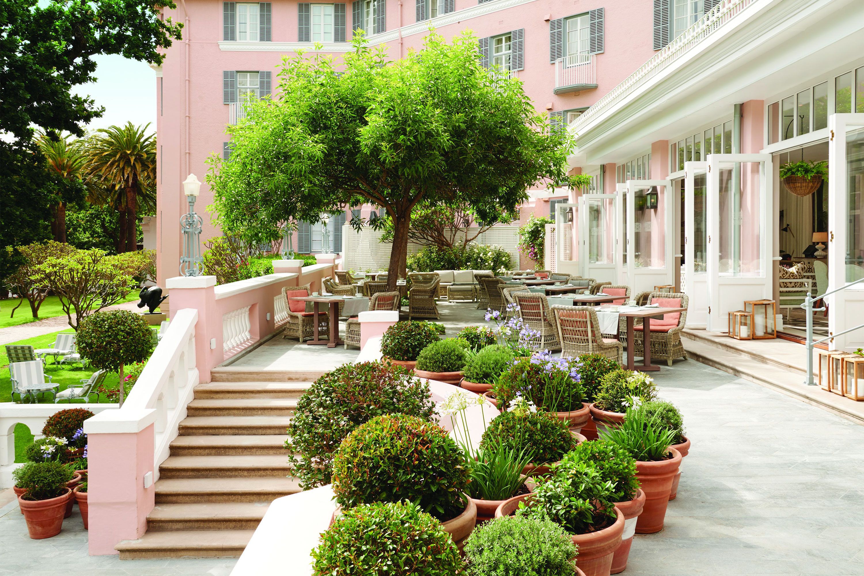 Tables and chairs on a garden setting at an outdoor patio of a restaurant. 