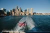 The US flag flies on the back of a boat sailing through Boston Harbor in Massachusetts on a sunny day