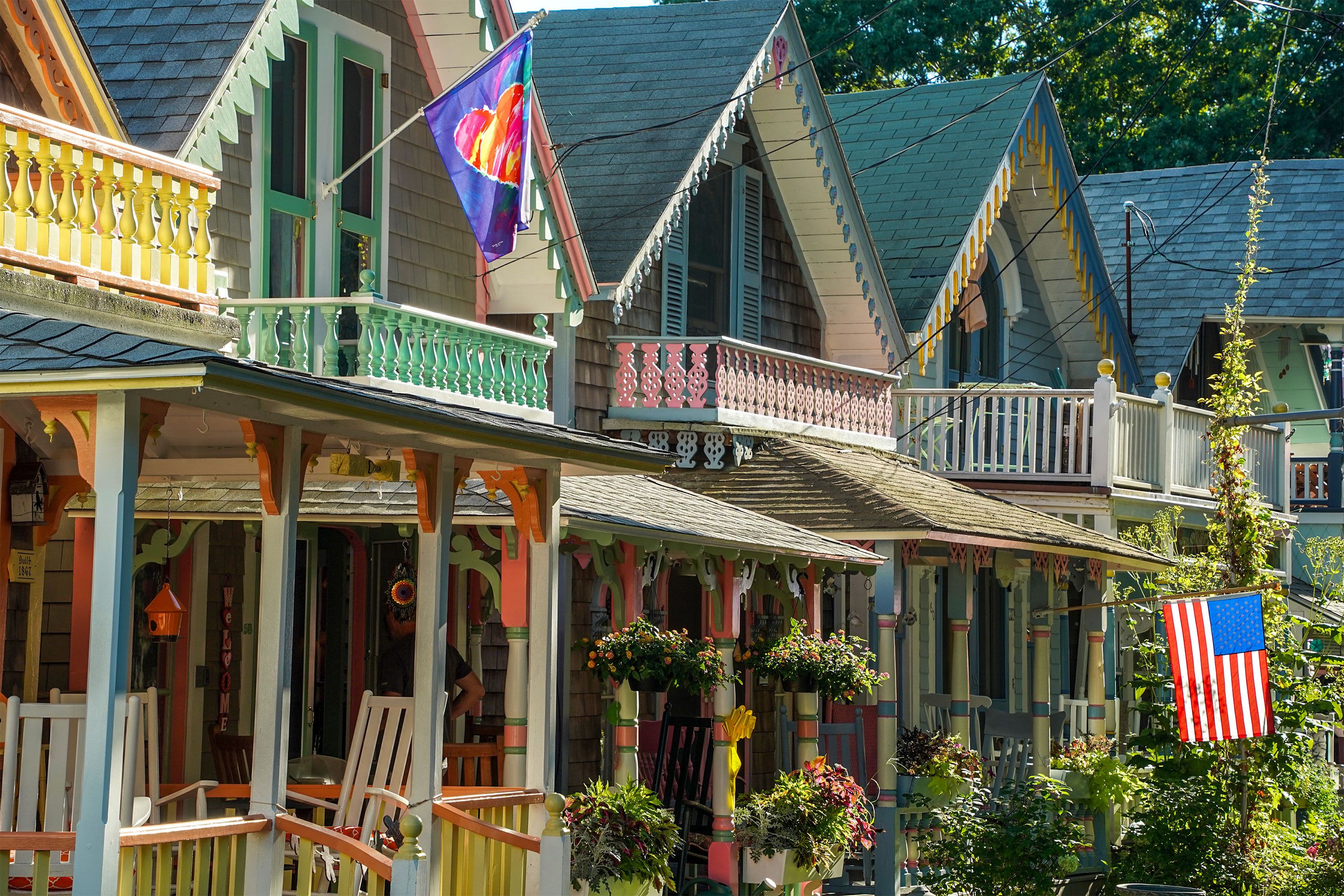 Colorful Victorian-era gingerbread cottages in Oak Bluffs, Martha’s Vineyard, with ornate wooden trim and pastel paint, lined up along a quiet street.