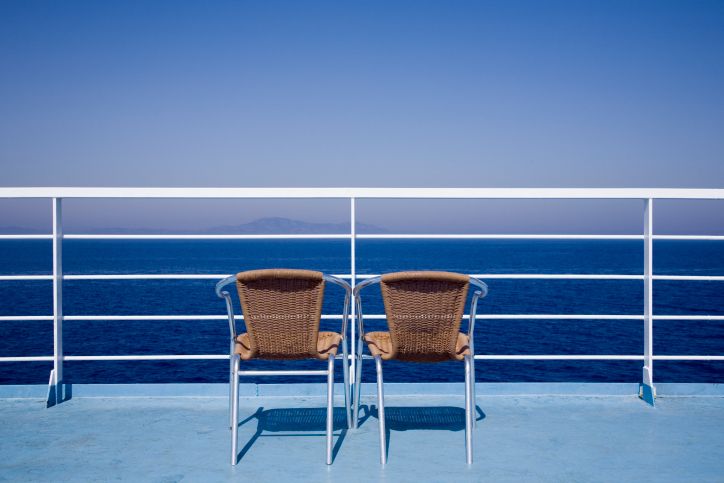 Two empty chairs on a cruise ship deck, looking at the ocean.