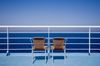 Two empty chairs on a cruise ship deck, looking at the ocean.