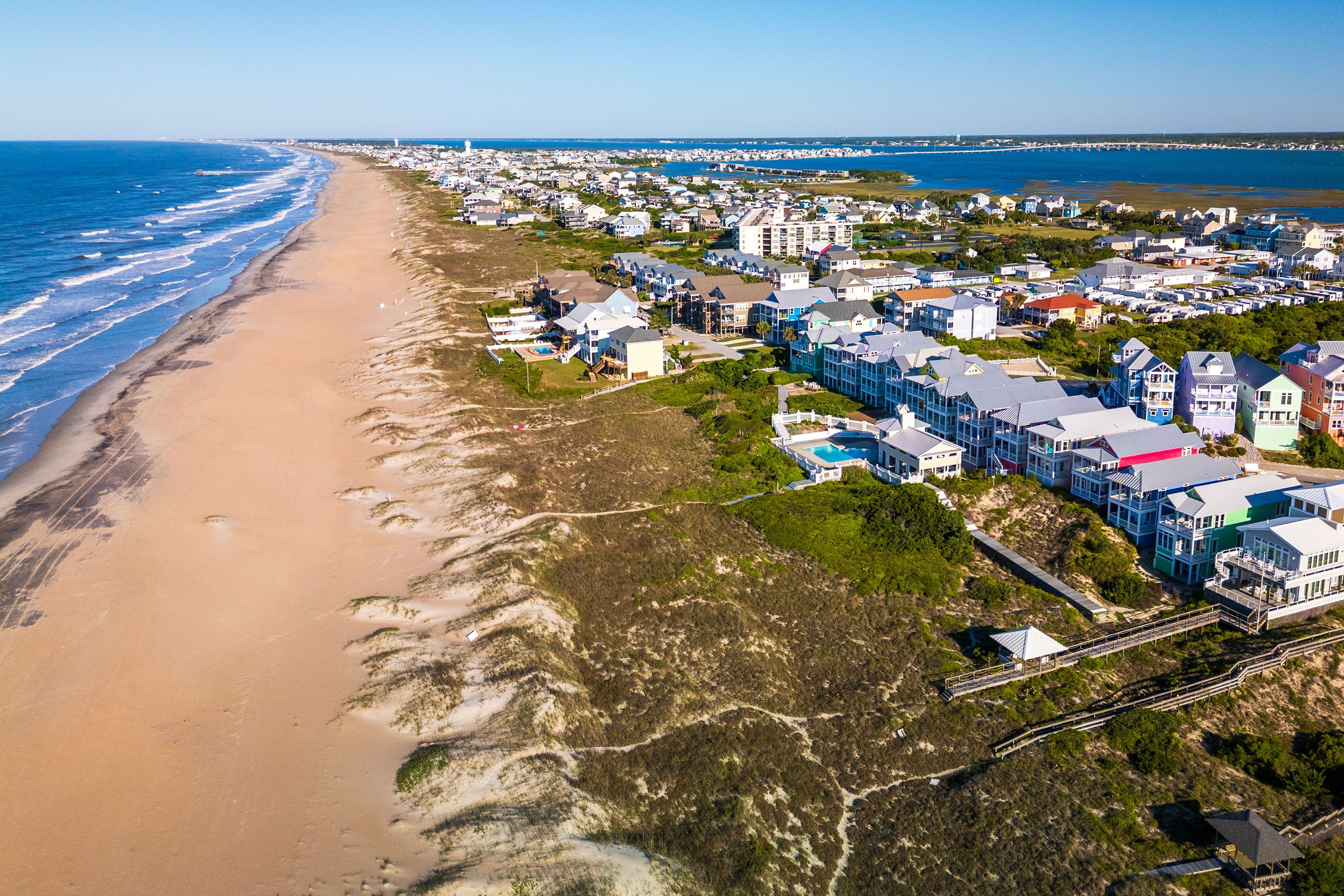 An expansive sandy shore, gentle Atlantic surf, and a bright, clear sky, evoking a peaceful seaside escape.