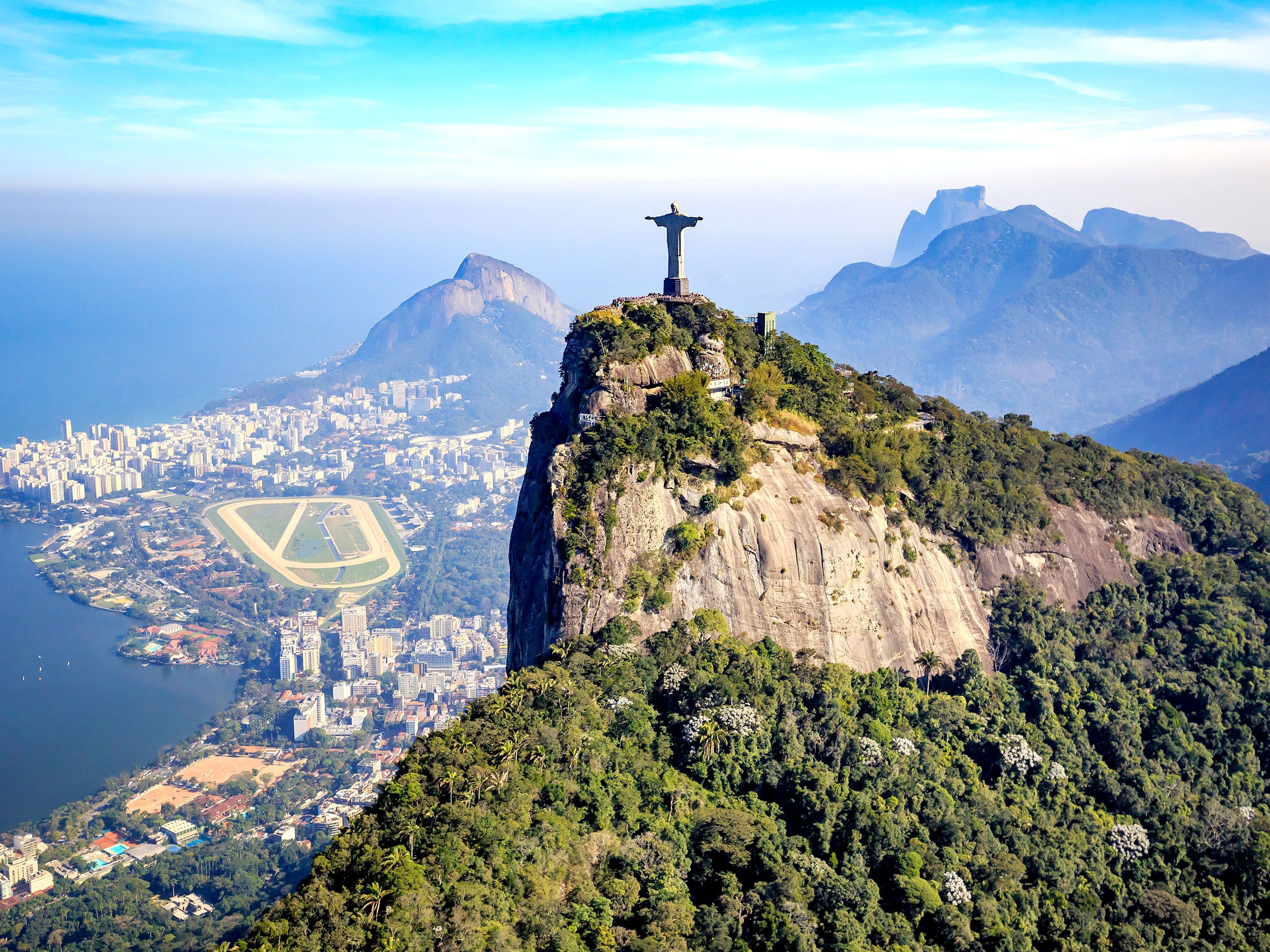 Aerial view of Christ on top of a mountain with ocean below.